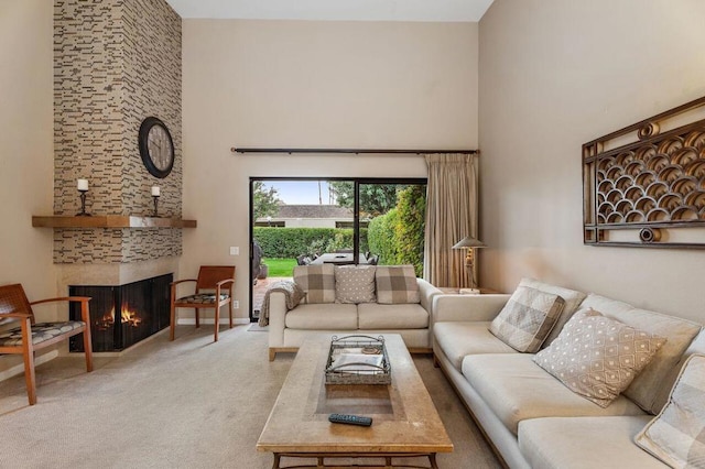 carpeted living room with a large fireplace and a high ceiling