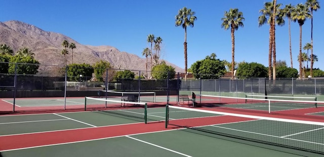 view of tennis court with a mountain view and basketball hoop