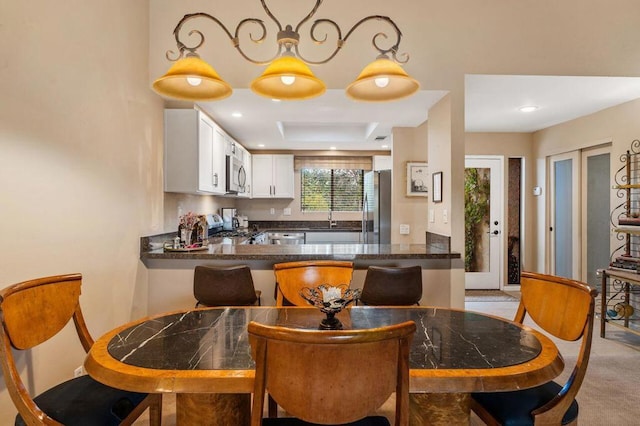 kitchen with white cabinetry, kitchen peninsula, appliances with stainless steel finishes, french doors, and hanging light fixtures