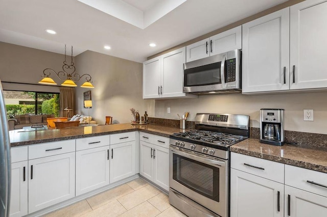 kitchen featuring hanging light fixtures, white cabinets, appliances with stainless steel finishes, and dark stone countertops