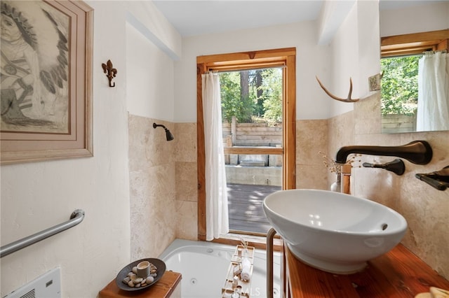 bathroom featuring vanity, tile walls, and a bath