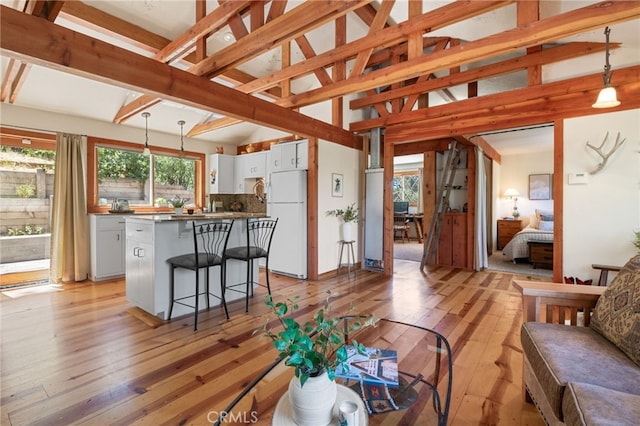 living room with high vaulted ceiling, light hardwood / wood-style flooring, and beamed ceiling