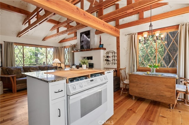 kitchen featuring white cabinets, decorative light fixtures, white range with gas cooktop, beamed ceiling, and a notable chandelier