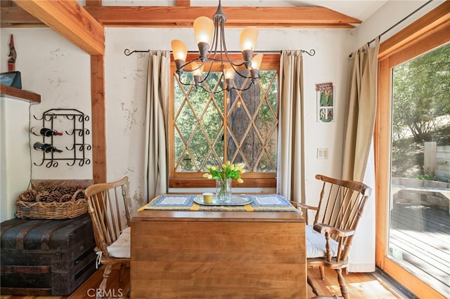 dining area with wood-type flooring, a wealth of natural light, and a notable chandelier