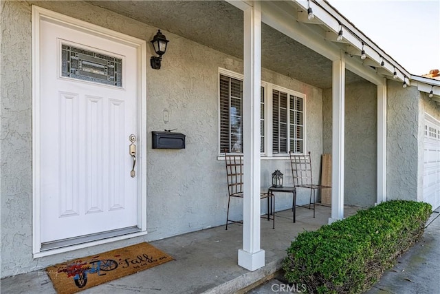 view of exterior entry with a garage and a porch