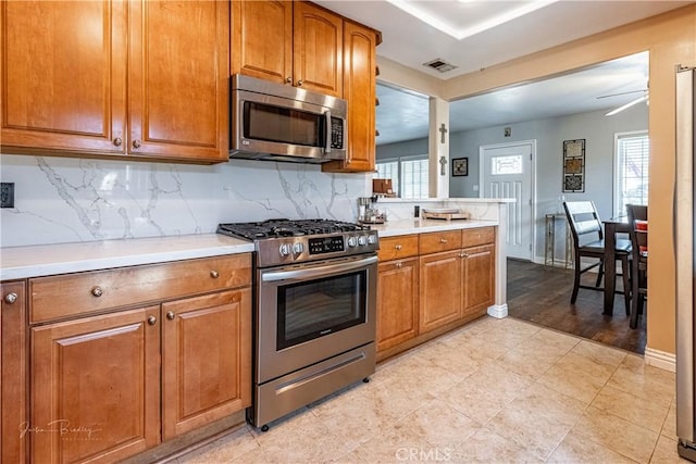 kitchen with decorative backsplash, plenty of natural light, stainless steel appliances, and ceiling fan