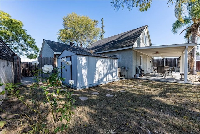 rear view of property with ceiling fan, a shed, and a patio