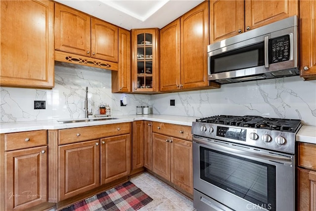 kitchen with tasteful backsplash, sink, appliances with stainless steel finishes, light tile patterned floors, and light stone counters