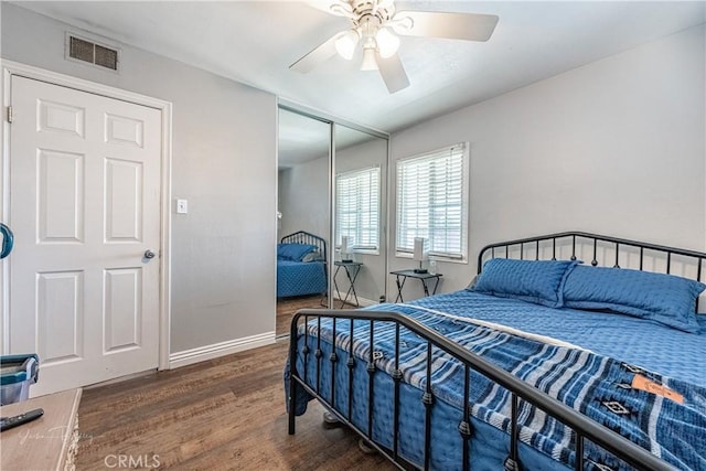 bedroom with dark wood-type flooring, ceiling fan, and a closet