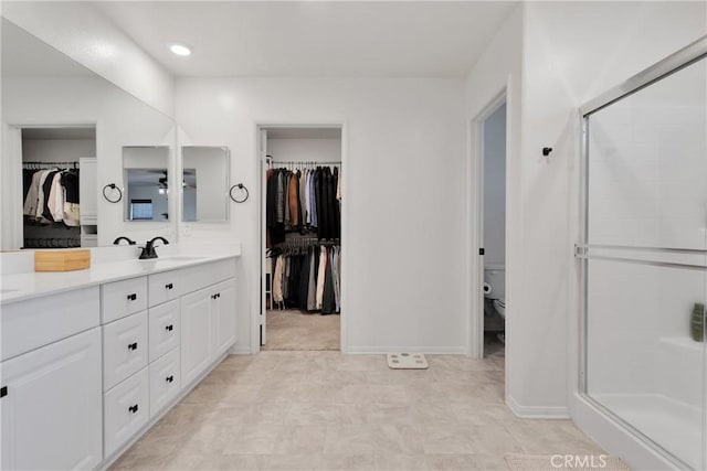 bathroom with toilet, vanity, and a shower with shower door