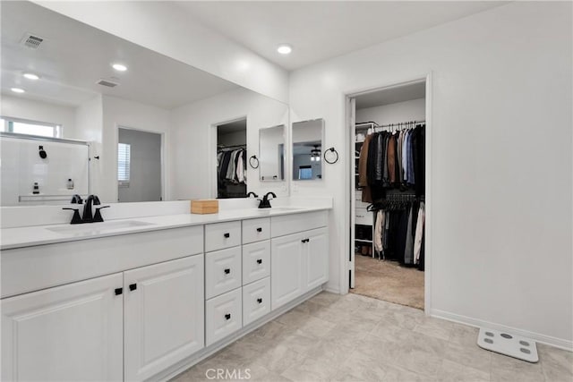 bathroom featuring a shower with door and vanity