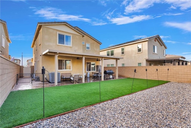 rear view of property with ceiling fan, cooling unit, a yard, and a patio