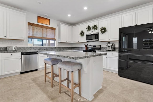 kitchen featuring a breakfast bar area, appliances with stainless steel finishes, white cabinetry, and a center island