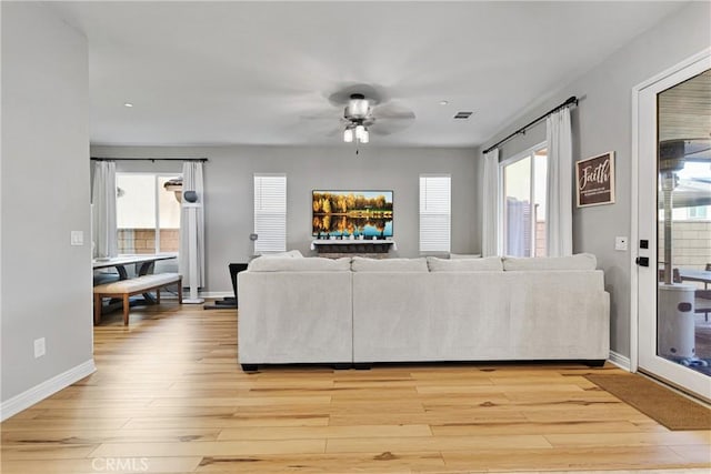 living room with ceiling fan, a healthy amount of sunlight, and light wood-type flooring