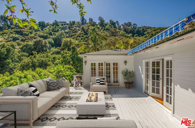 wooden terrace featuring an outdoor living space with a fire pit and french doors