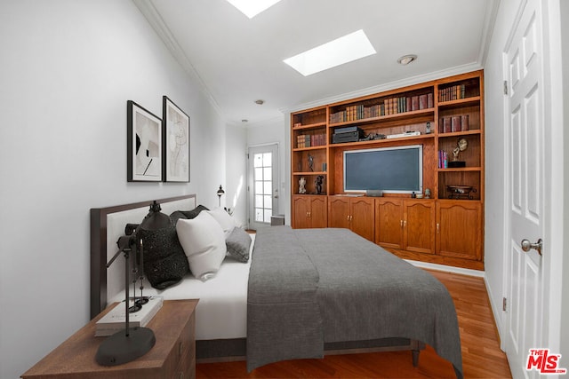 bedroom featuring a skylight, crown molding, and light hardwood / wood-style flooring