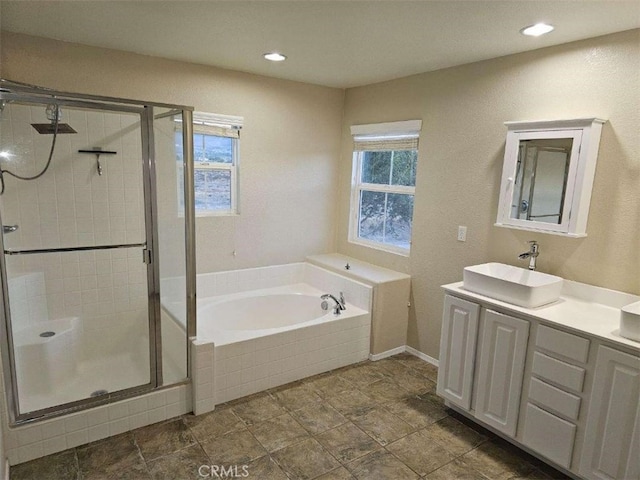 bathroom with a wealth of natural light, separate shower and tub, and vanity