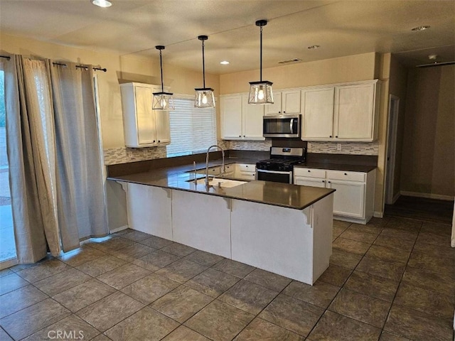 kitchen featuring sink, kitchen peninsula, white cabinets, and stainless steel appliances