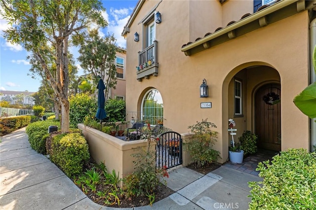 entrance to property with fence, a gate, and stucco siding