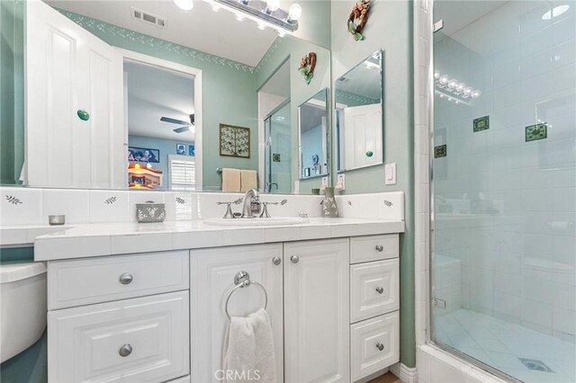 bathroom featuring ceiling fan, vanity, and a shower with door