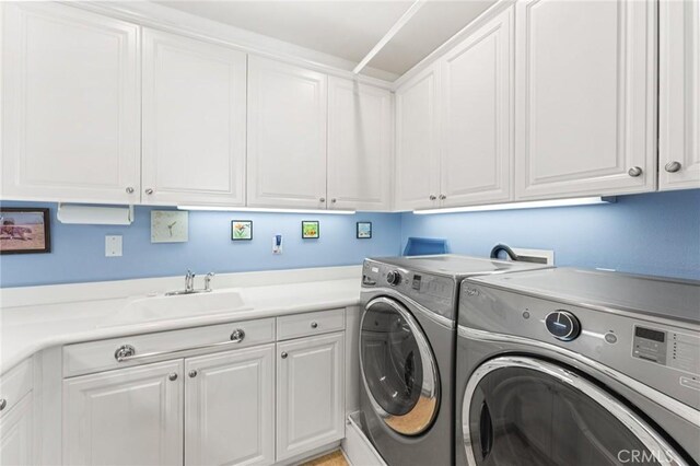 clothes washing area featuring cabinets, sink, and washer and dryer