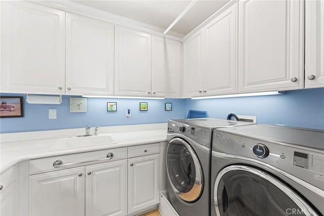 washroom featuring cabinet space, a sink, and independent washer and dryer