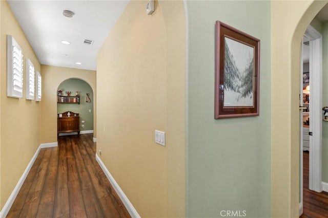 hall with baseboards, visible vents, arched walkways, dark wood-type flooring, and recessed lighting