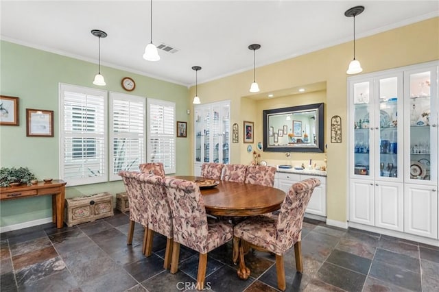 dining area with baseboards, visible vents, crown molding, and stone tile floors