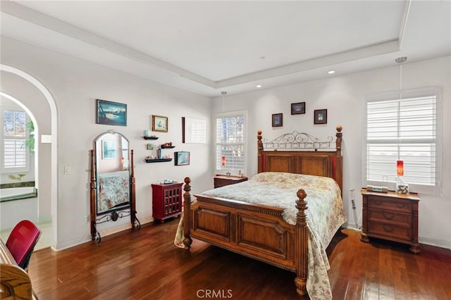 bedroom with dark wood-style floors, baseboards, a tray ceiling, and recessed lighting