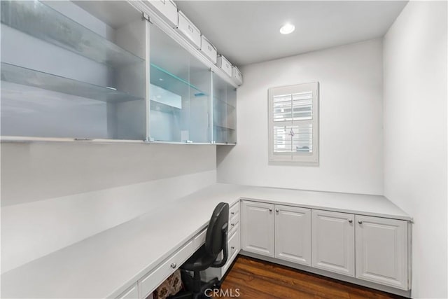 unfurnished office featuring dark wood-style floors, recessed lighting, and built in desk