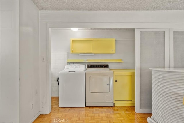 clothes washing area featuring light parquet flooring, independent washer and dryer, a textured ceiling, and cabinets