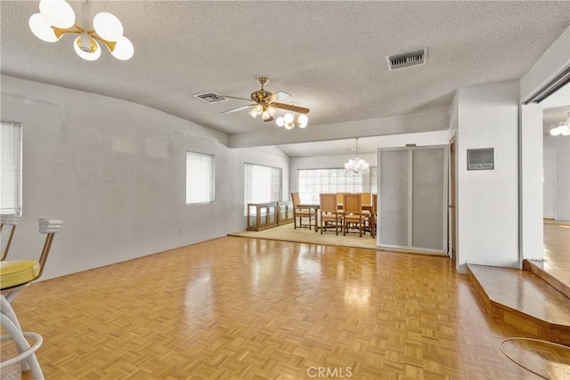 unfurnished living room with ceiling fan with notable chandelier, light parquet flooring, and a textured ceiling