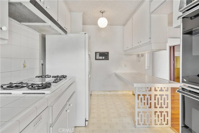 kitchen with tile countertops, white cabinets, hanging light fixtures, a textured ceiling, and white gas cooktop