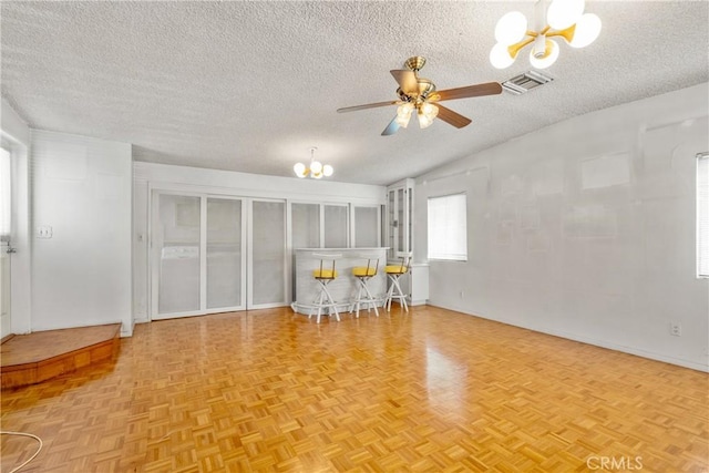 unfurnished living room featuring light parquet flooring, vaulted ceiling, ceiling fan with notable chandelier, and a textured ceiling