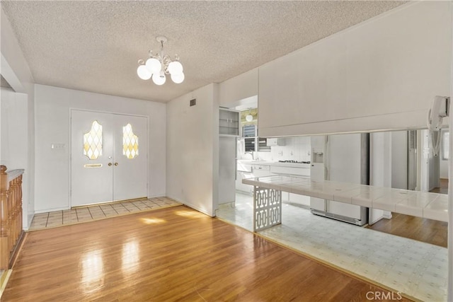 interior space featuring light hardwood / wood-style flooring, sink, a chandelier, and a textured ceiling