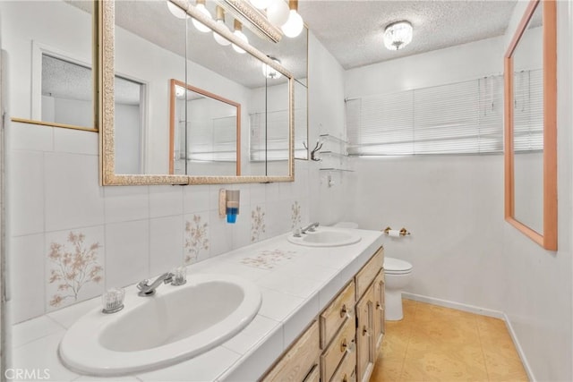 bathroom with toilet, vanity, tile patterned flooring, and a textured ceiling