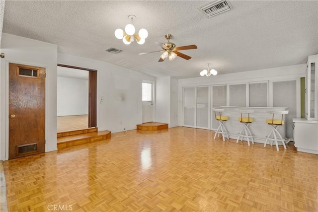 unfurnished living room featuring light parquet flooring, ceiling fan with notable chandelier, and a textured ceiling