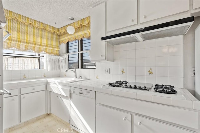 kitchen with white dishwasher, decorative light fixtures, white cabinetry, and tile countertops