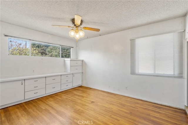 unfurnished bedroom featuring ceiling fan, a textured ceiling, and light hardwood / wood-style flooring