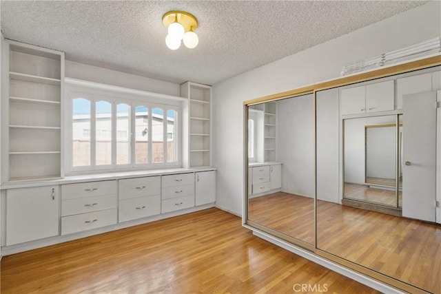 unfurnished bedroom with a textured ceiling, a closet, and light wood-type flooring