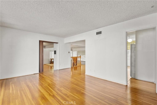 empty room with wood-type flooring and a textured ceiling