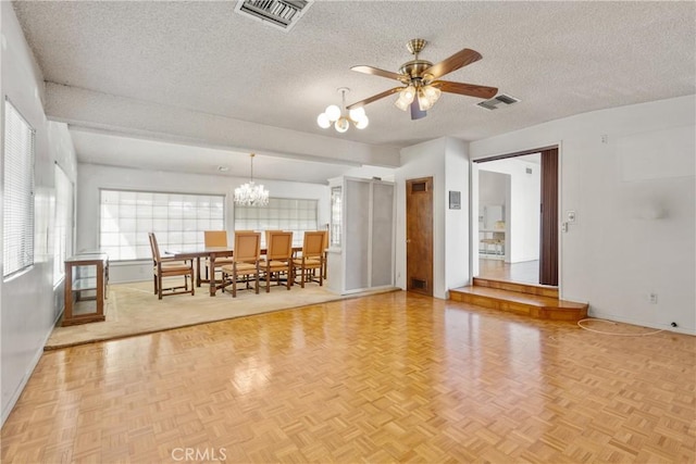 unfurnished living room with parquet flooring, ceiling fan with notable chandelier, and a textured ceiling