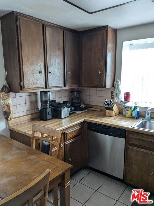 kitchen with dark brown cabinets, stainless steel dishwasher, and tasteful backsplash