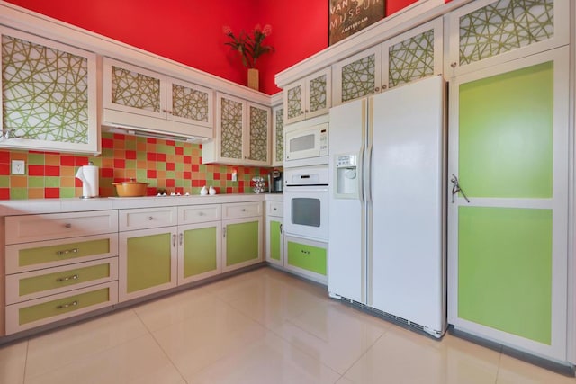 kitchen featuring white appliances, light tile patterned floors, a towering ceiling, and tasteful backsplash