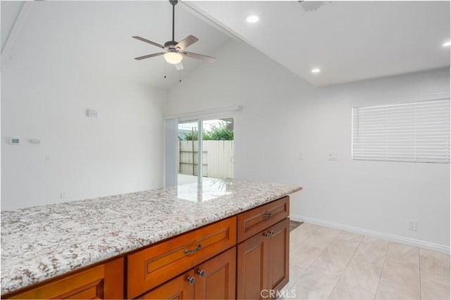 kitchen featuring ceiling fan, light stone countertops, and lofted ceiling