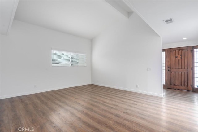 spare room with lofted ceiling and wood-type flooring