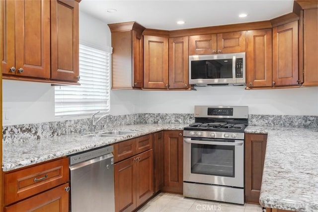 kitchen with light tile patterned floors, light stone countertops, sink, and stainless steel appliances