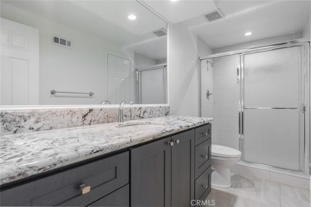 bathroom featuring toilet, vanity, and a shower with door