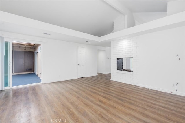 unfurnished living room with rail lighting, hardwood / wood-style floors, a brick fireplace, high vaulted ceiling, and beamed ceiling