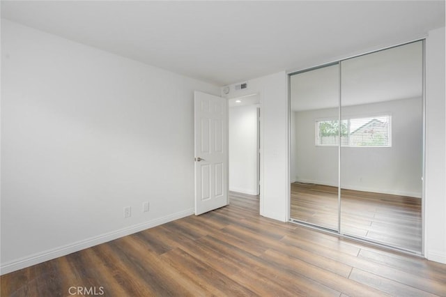 unfurnished bedroom featuring a closet and dark hardwood / wood-style flooring